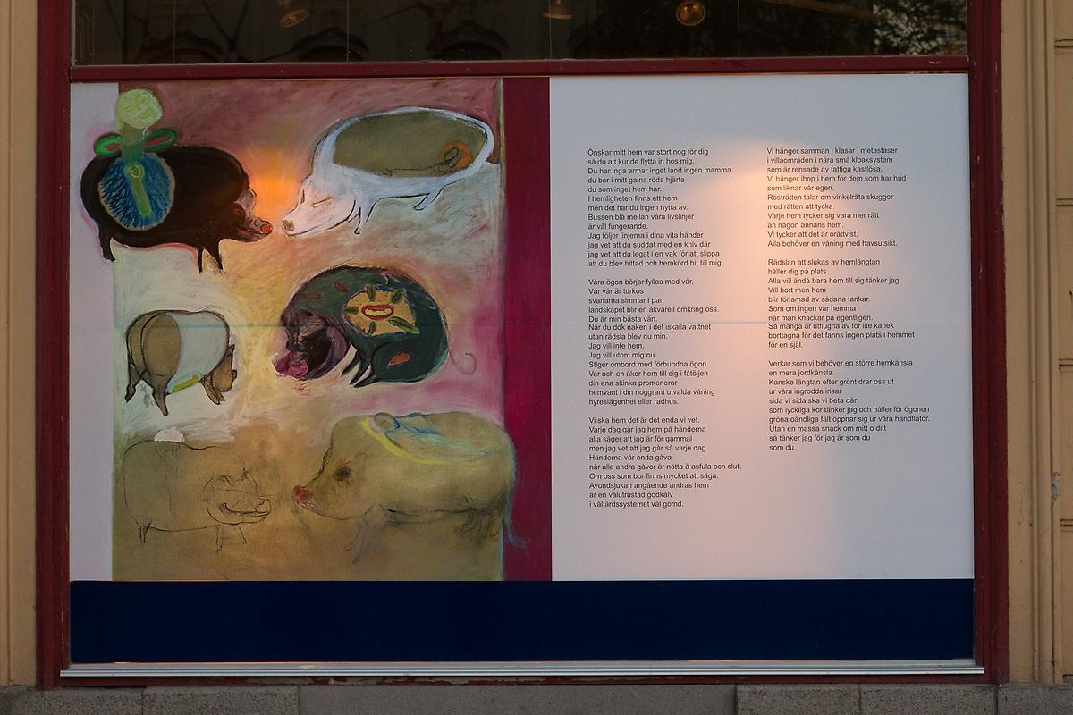 Närbild på en affisch i Lindhska bokhandelns skyltfönster.  Affisch efterliknar ett stort bok uppslag. På vänstra boksidan är det en teckning på sex grisar i olika storlekar och färger, på högra boksidan är det en lång text.